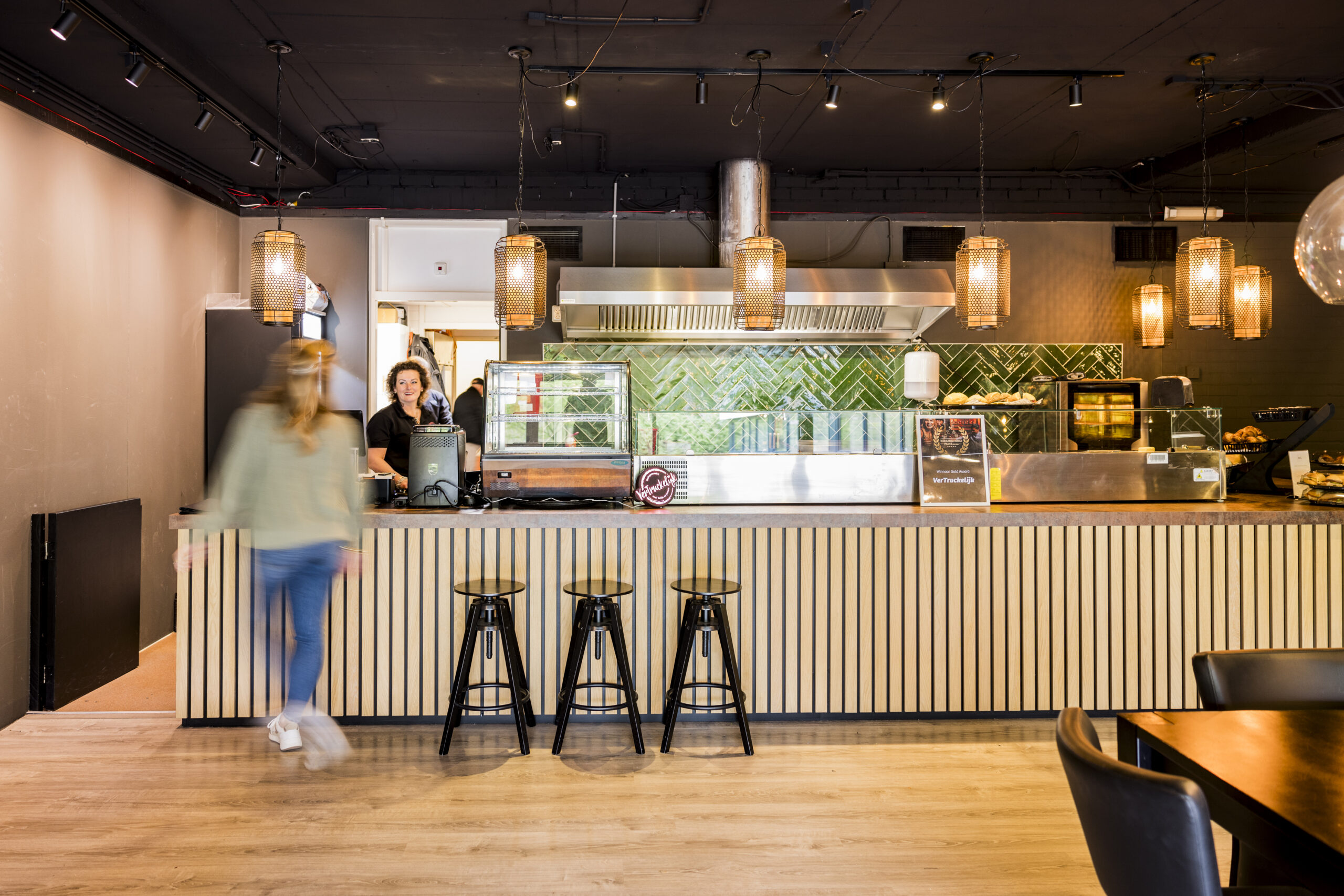 Een modern restaurantinterieur met een balie, stoelen en sfeervolle hanglampen.