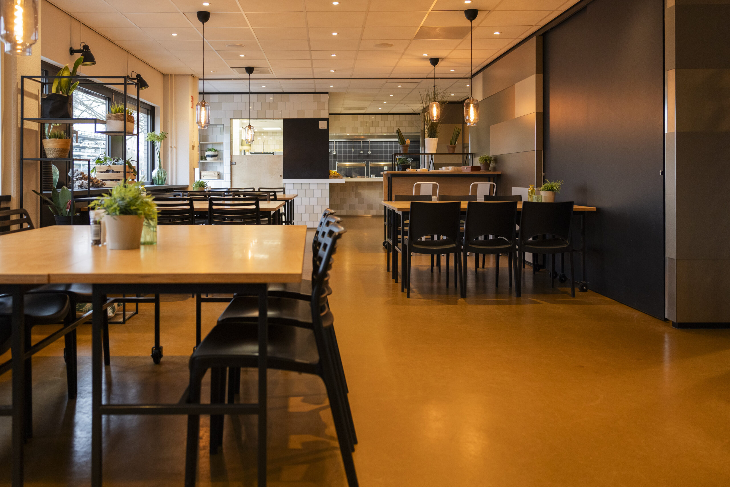 Het interieur van restaurant ELE_UTR_Winthontlaan_21 met moderne tafels, stoelen en planten.