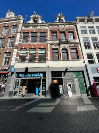 Voorgevel van een historisch gebouw aan het Damrak met een Albert Heijn to go-winkel op de begane grond.