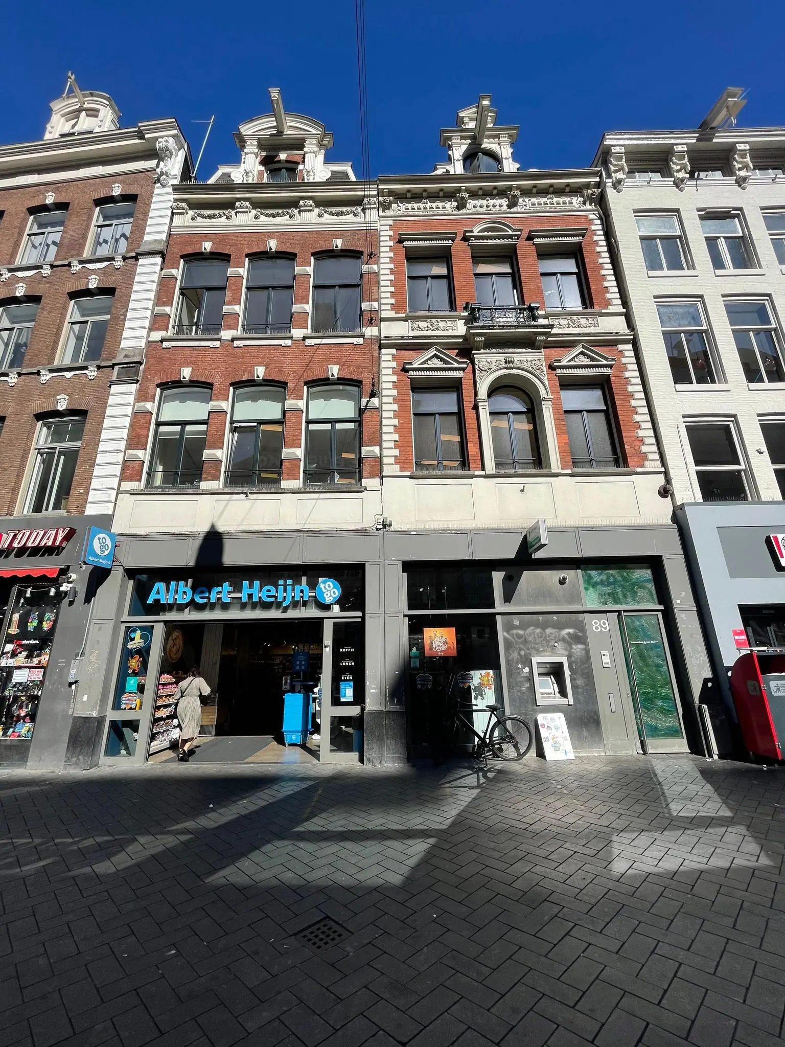 Voorgevel van een historisch gebouw aan het Damrak met een Albert Heijn to go-winkel op de begane grond.