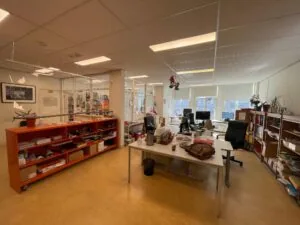 Een modern kantoor aan het Damrak met meerdere bureaus, computers en open kasten vol documenten en kantoorartikelen.