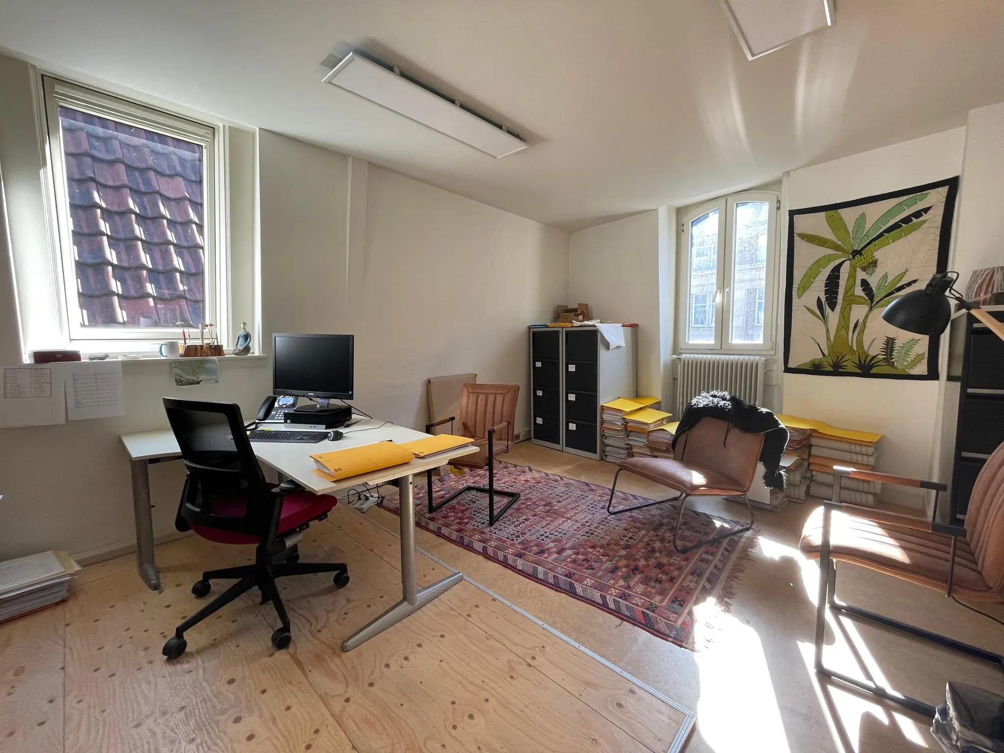 Licht kantoor op Damrak met bureaus, stoelen, archiefkasten en stapels dossiers.
