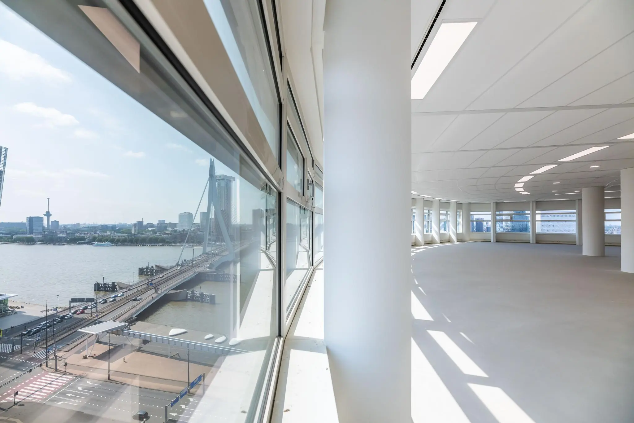 Licht en modern kantoorpand met uitzicht op de Erasmusbrug vanaf Wilhelminaplein in Rotterdam.