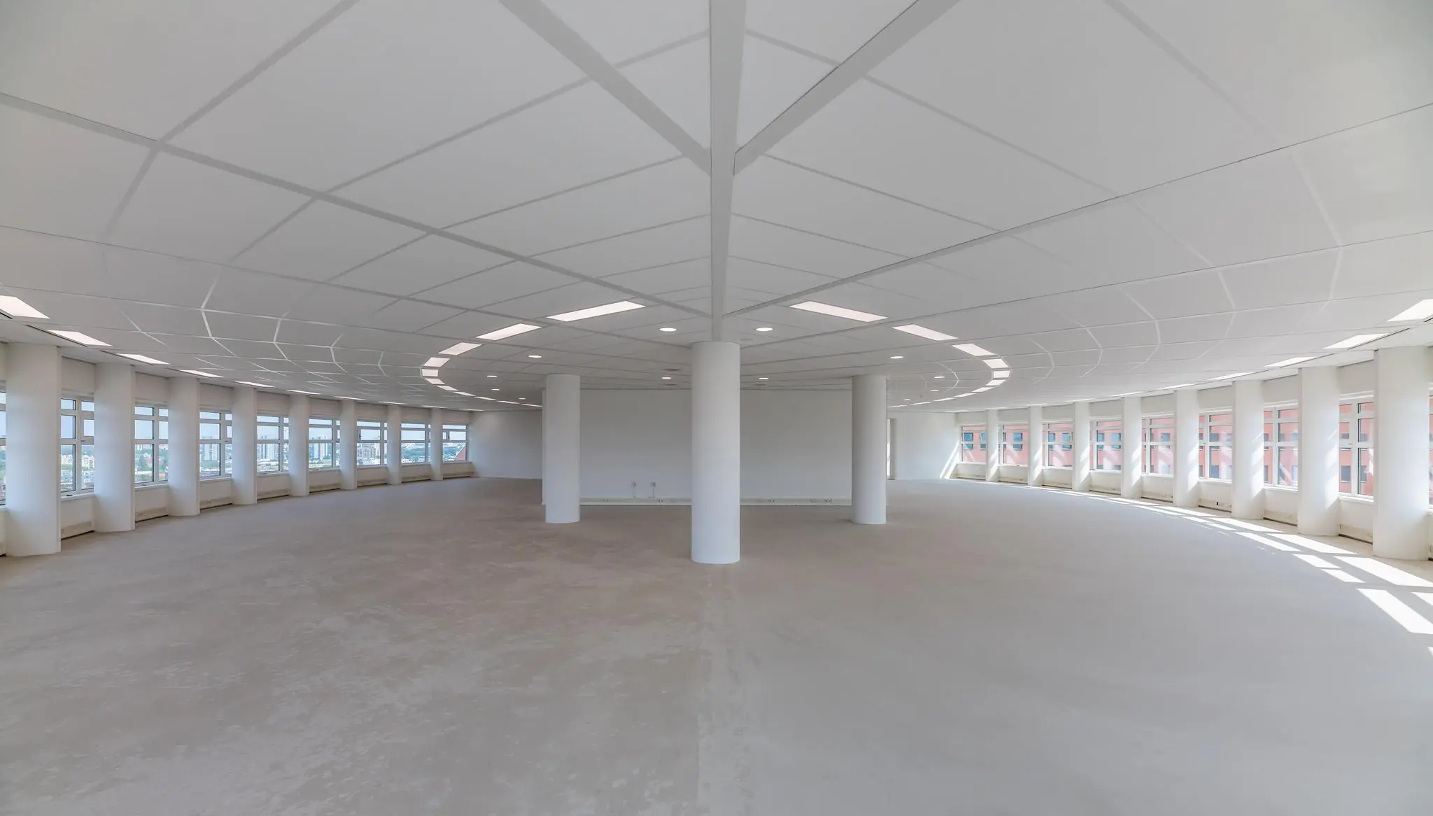 Lichte, lege kantoorruimte met ronde vorm en grote ramen aan het Wilhelminaplein.