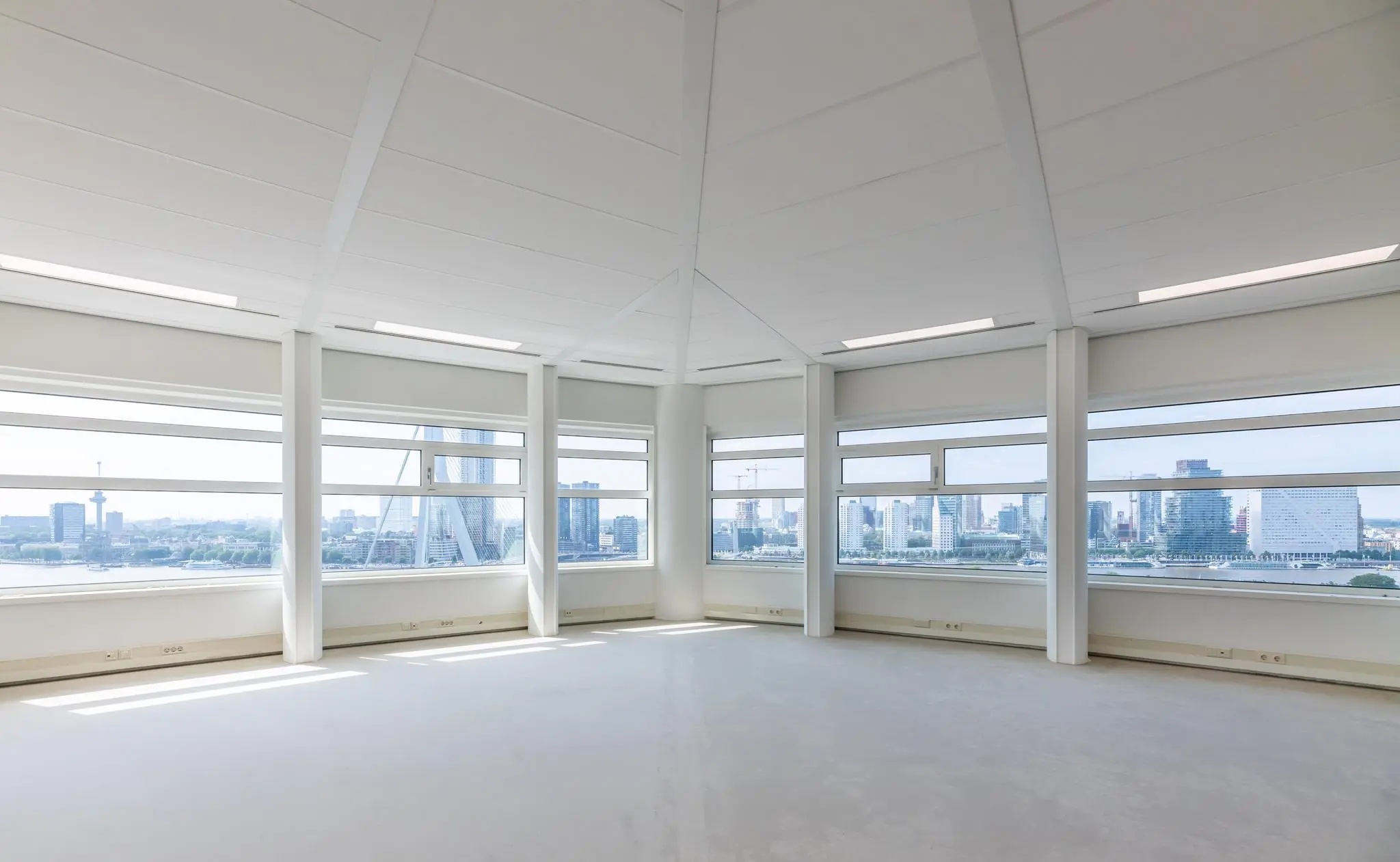 Lichte, lege kantoorruimte op het Wilhelminaplein met panoramisch uitzicht over de skyline van Rotterdam en de Erasmusbrug.
