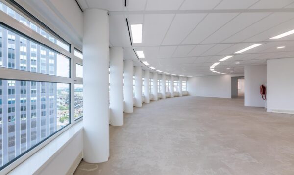 Licht en modern leeg kantoorpand aan het Wilhelminaplein met grote ramen en rondlopende gevel.