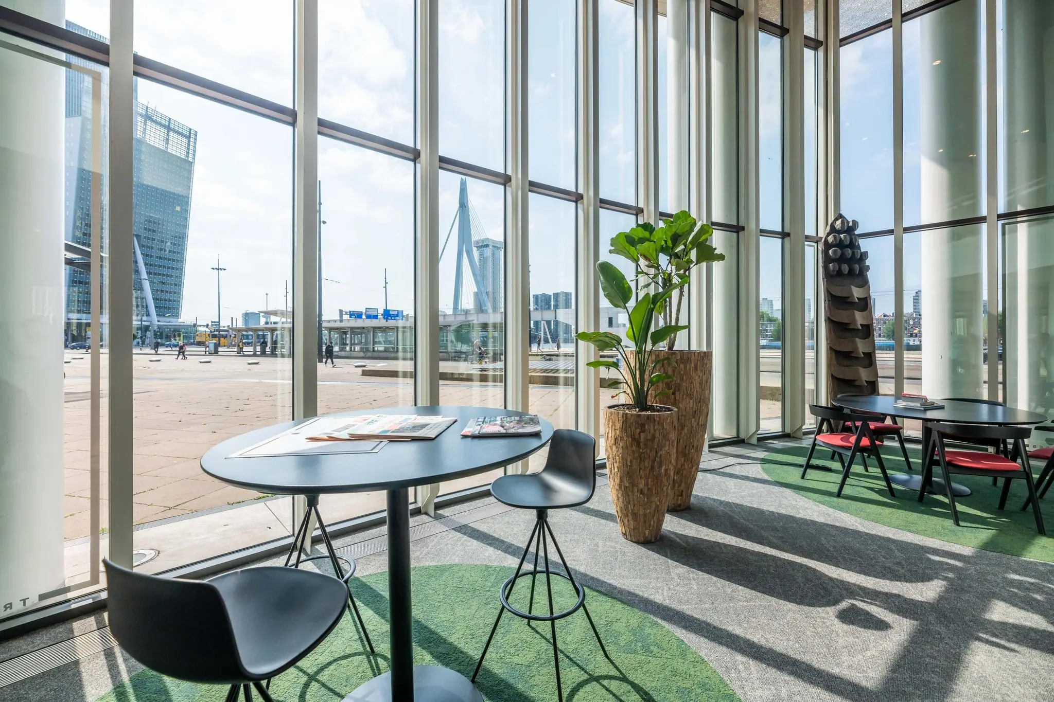 Moderne wachtruimte met uitzicht op het Wilhelminaplein en de Erasmusbrug in Rotterdam.