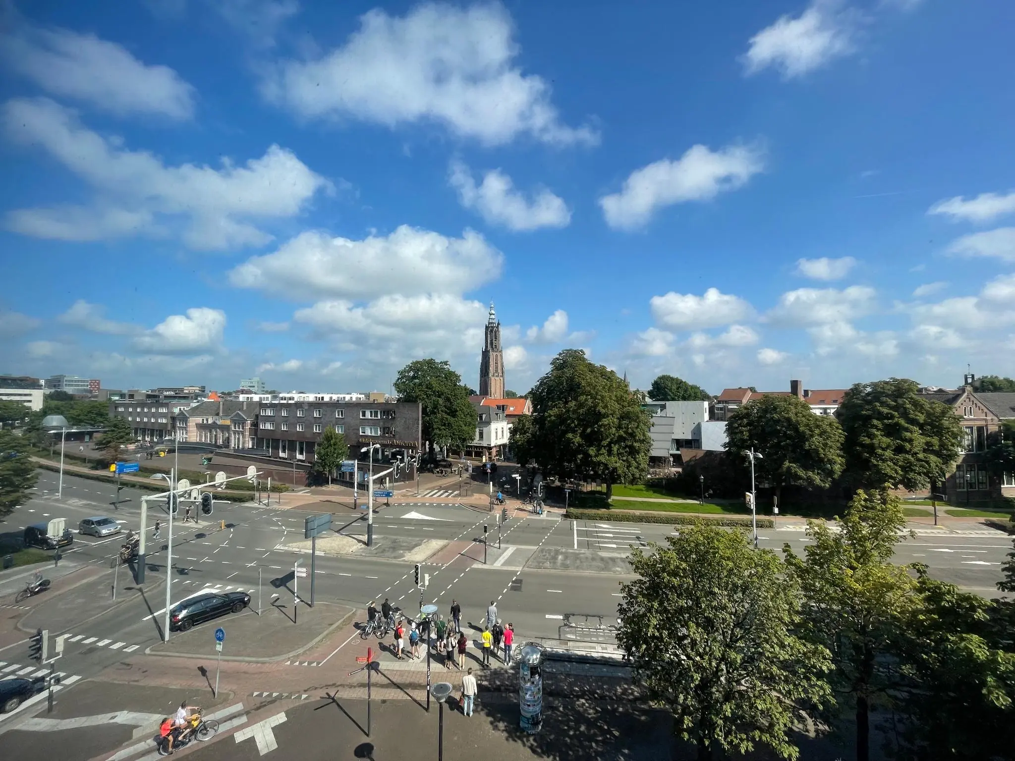 Drukke kruising op de Arnhemseweg in Amersfoort met op de achtergrond de Onze Lieve Vrouwetoren onder een blauwe lucht.
