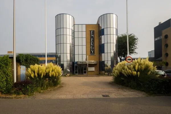 Vooraanzicht van het moderne kantoorgebouw aan de Kernkade 8 t/m 12 met spiegelende torens en omliggend groen.