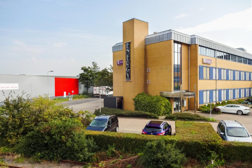 Kantoorpand aan de Kernkade met het bord "Energy" op de voorgevel en geparkeerde auto's op de voorgrond.