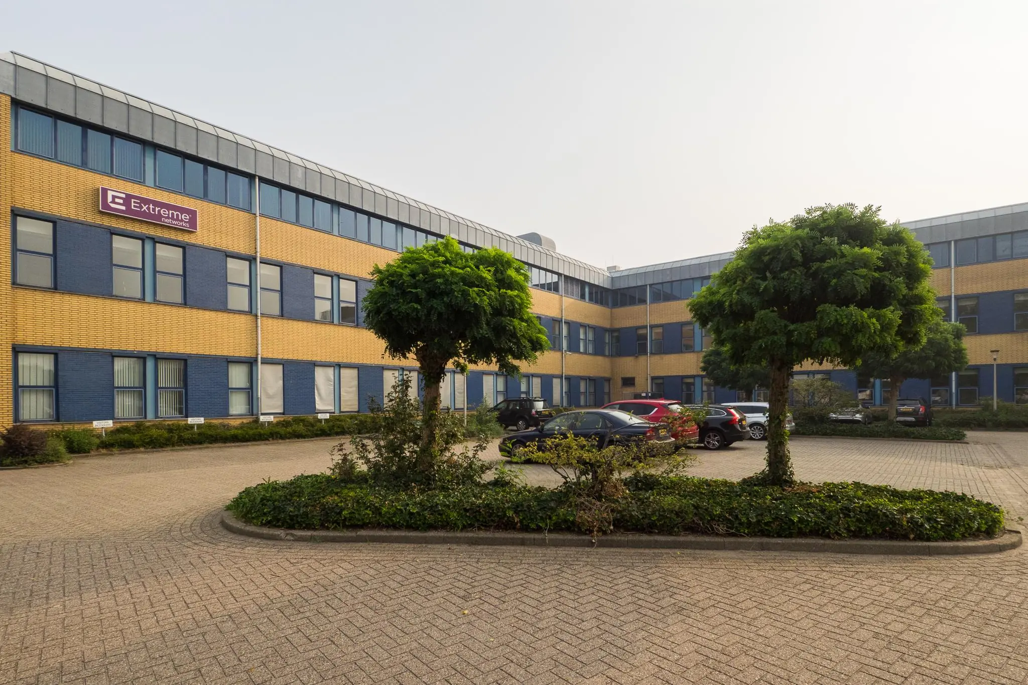 Kantoorgebouw aan de Kernkade met het logo van Extreme Networks en een parkeerplaats op de voorgrond.