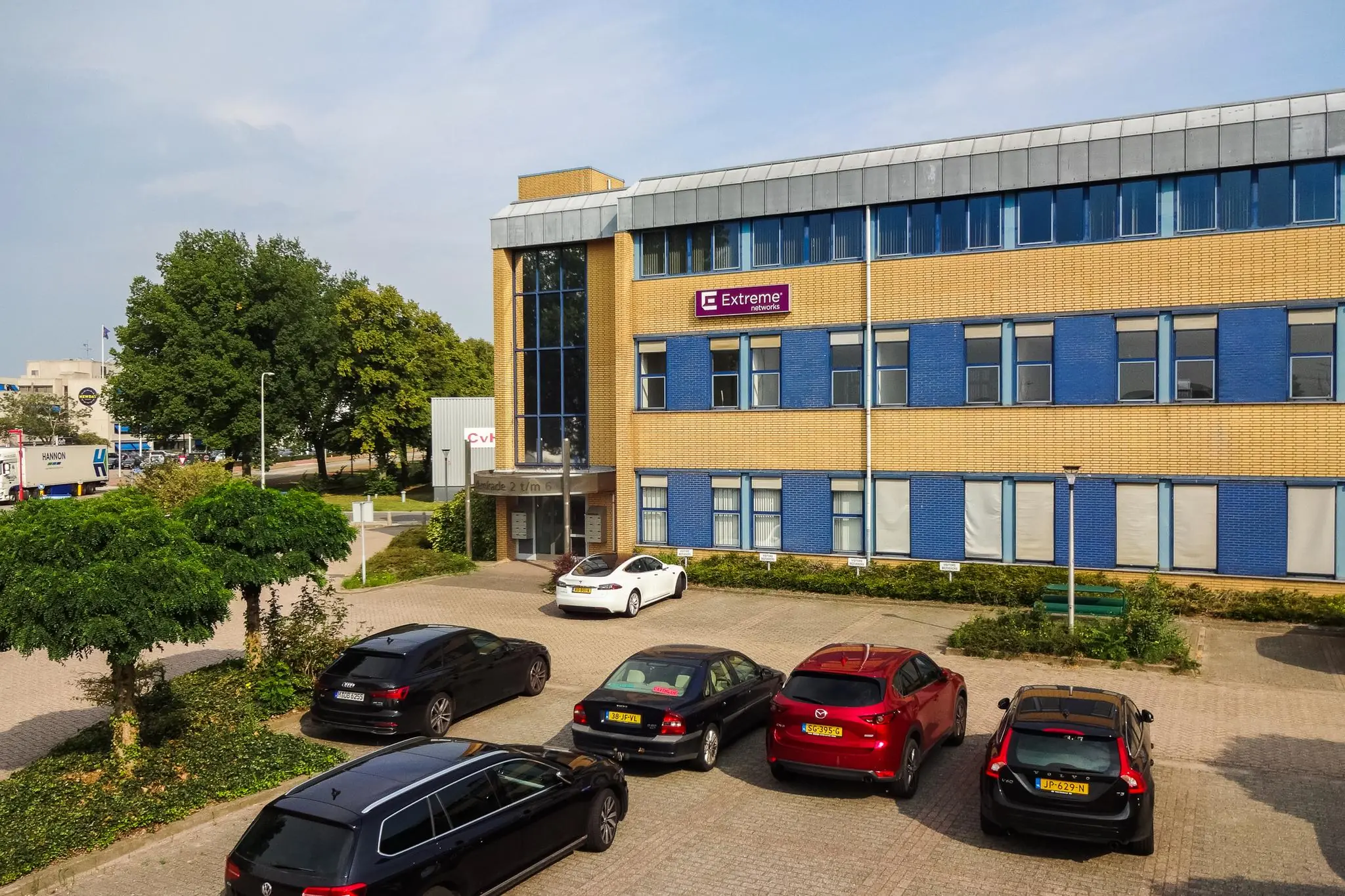 Kantoorgebouw aan de Kernkade met het logo van Extreme Networks en geparkeerde auto's op de voorgrond.