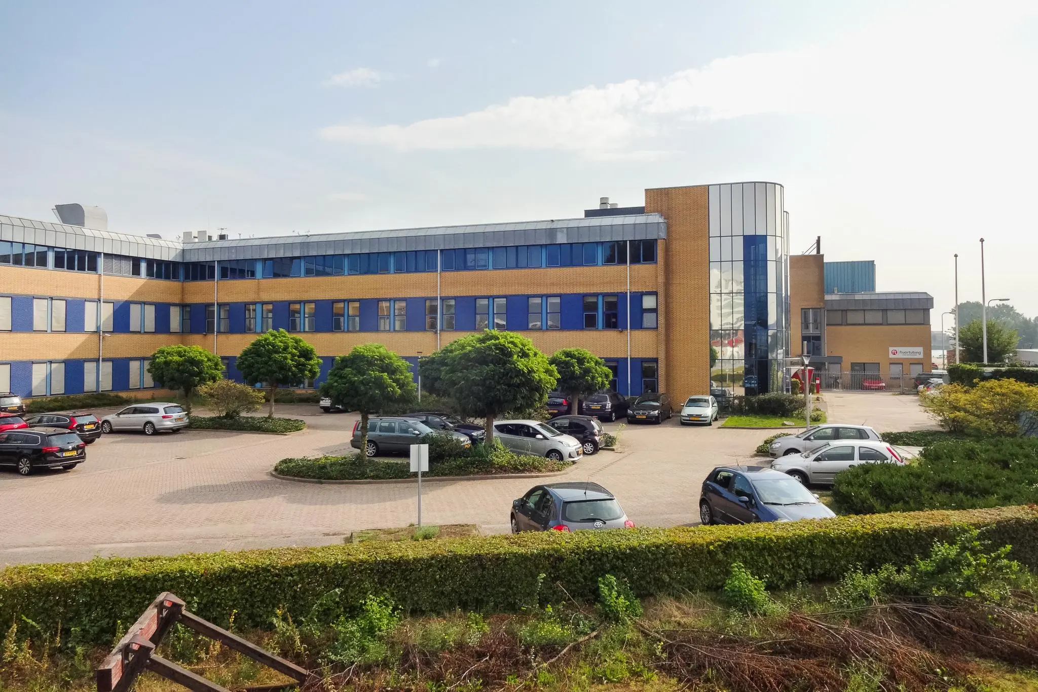 Kantoorpand aan de Kernkade met parkeerplaatsen en enkele geparkeerde auto's op de voorgrond.