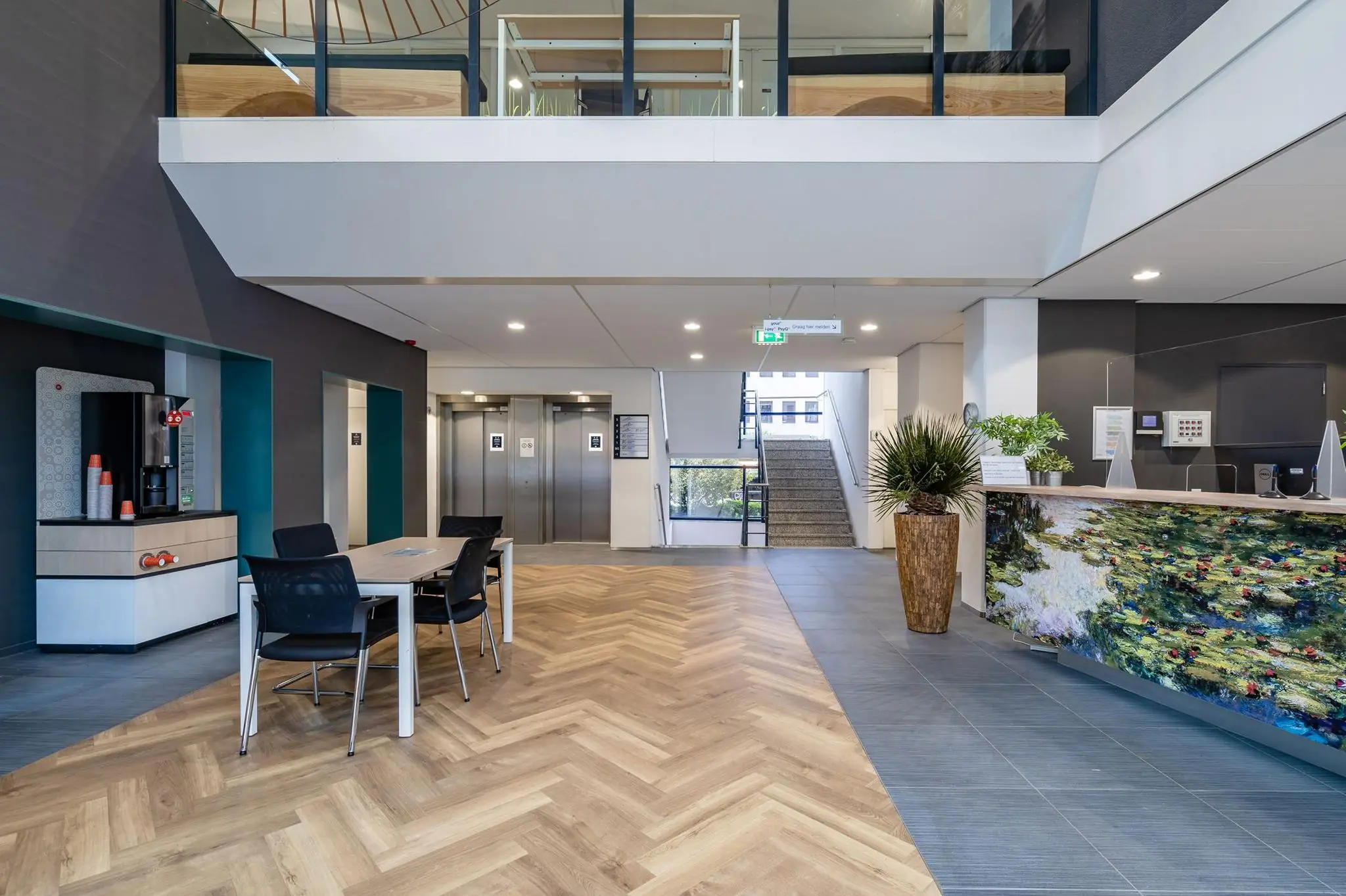 Moderne entreehal van een kantoorgebouw aan de Euclideslaan met receptiebalie, zitgedeelte, koffieautomaat en liften.