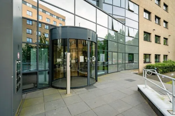 Ingang van een modern kantoorpand aan de Euclideslaan met een glazen draaideur en weerspiegelende gevel.