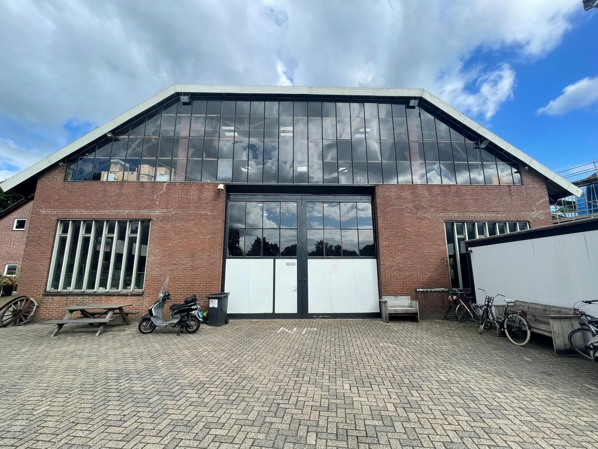 Vooraanzicht van een bakstenen loods aan de Sloterweg met grote ramen, fietsen en een scooter op de voorgrond.