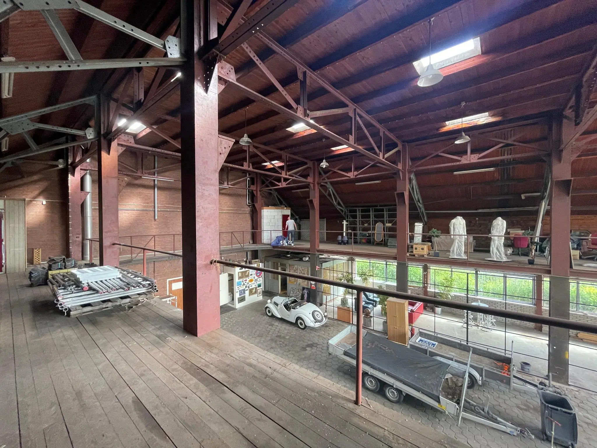 Industriële loods aan de Sloterweg met een houten verdiepingsvloer, stalen constructie en diverse opgeslagen materialen en voertuigen.