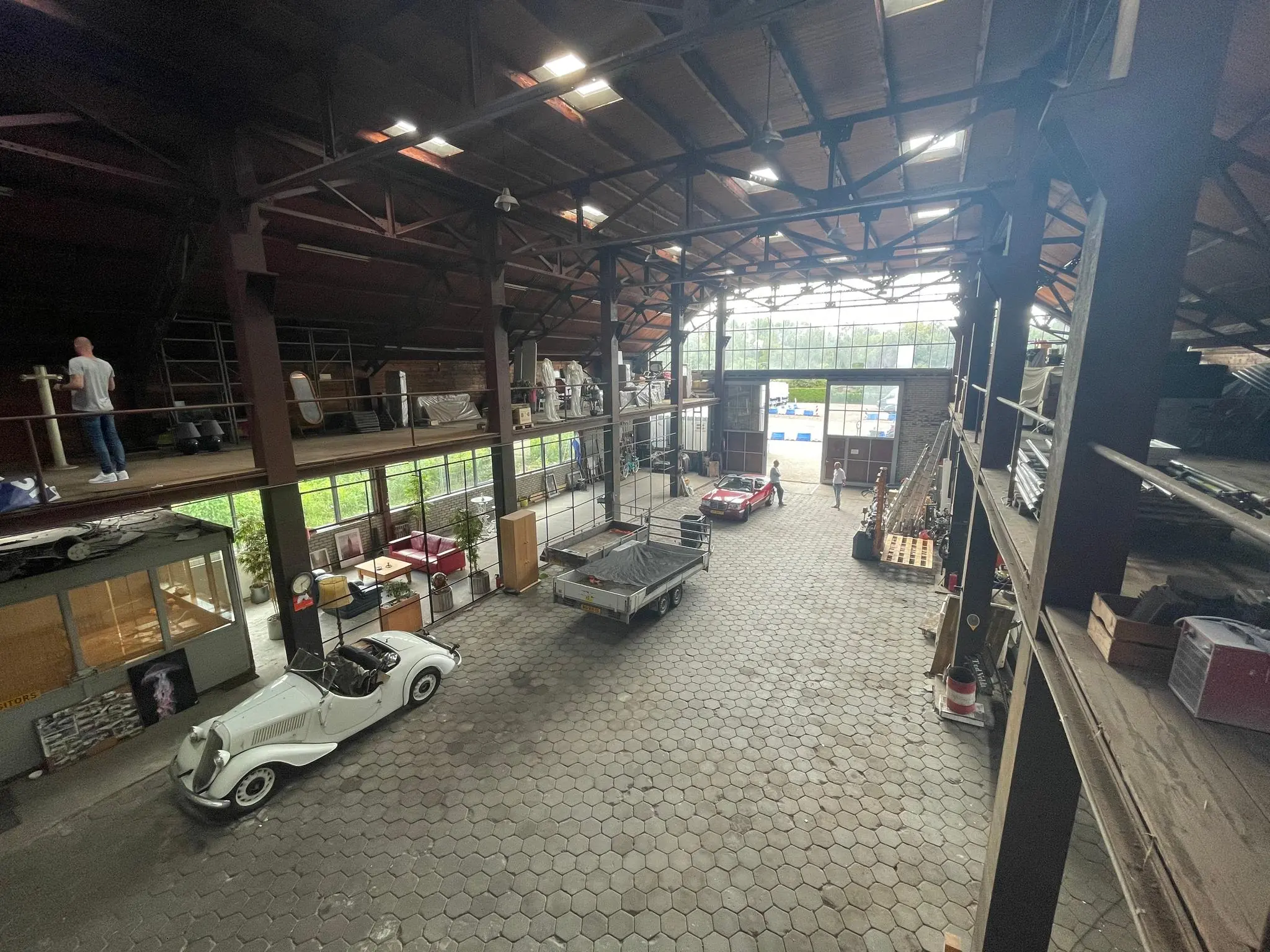 Grote industriële loods aan de Sloterweg met klassieke auto's, werkplekken en opslagruimte.