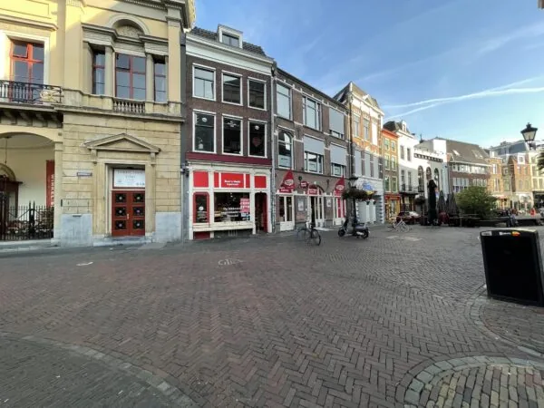 Straatbeeld van de Ganzenmarkt in Utrecht met historische gevels, winkels en terrassen op een rustige ochtend.