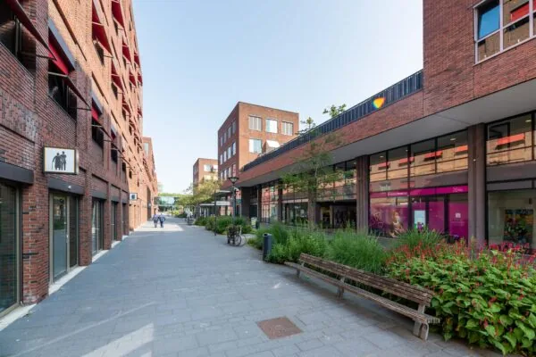 Moderne winkel- en woonstraat in de Haastrechtstraat met roodbruine bakstenen gebouwen, groenstroken en bankjes.