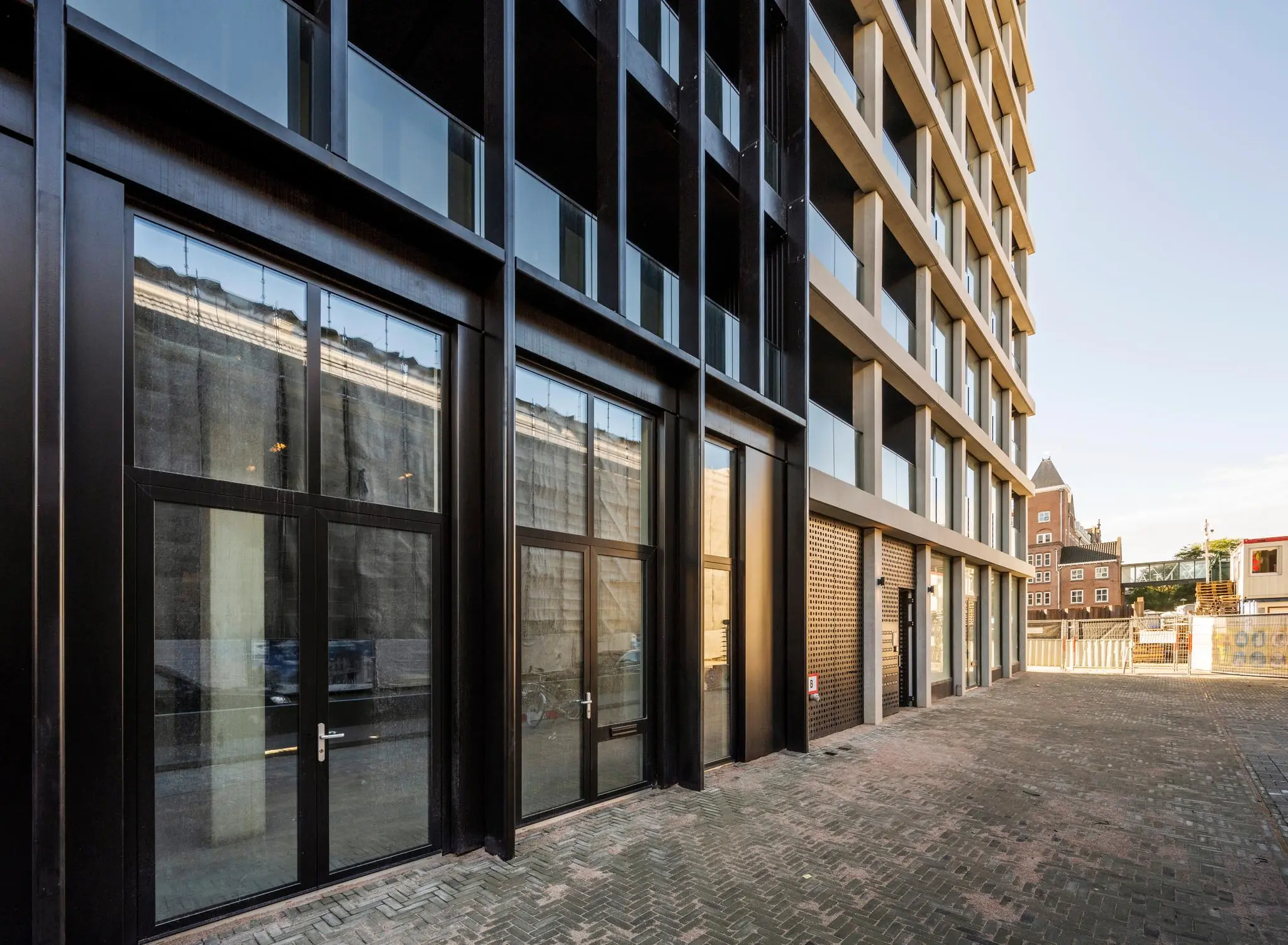 Moderne gevel van een appartementencomplex aan de Oostenburgermiddenstraat in Amsterdam met grote ramen en een betegeld voetpad.