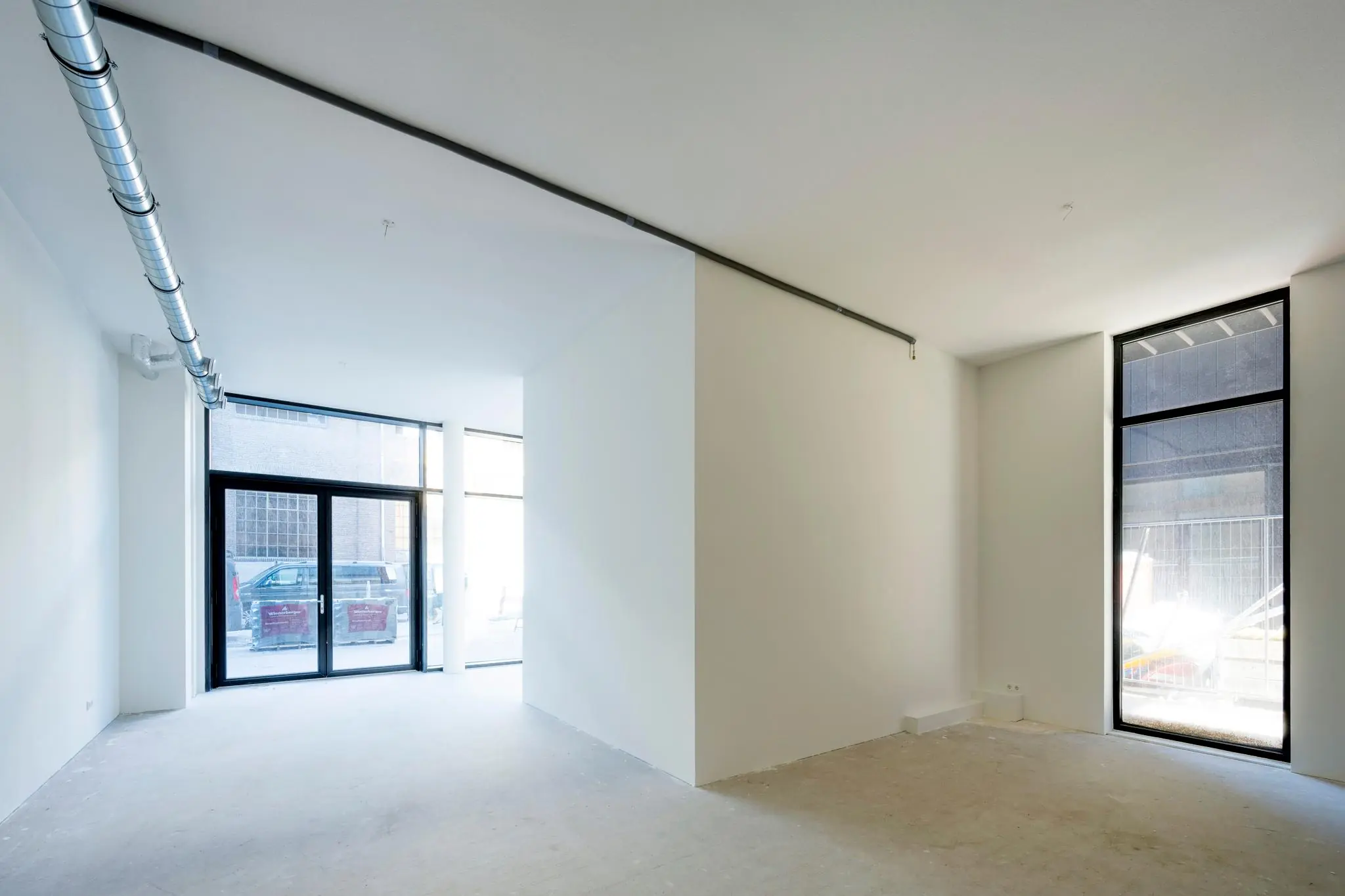 Leeg commercieel casco winkelpand aan de Oostenburgermiddenstraat met grote ramen en betonnen vloer.