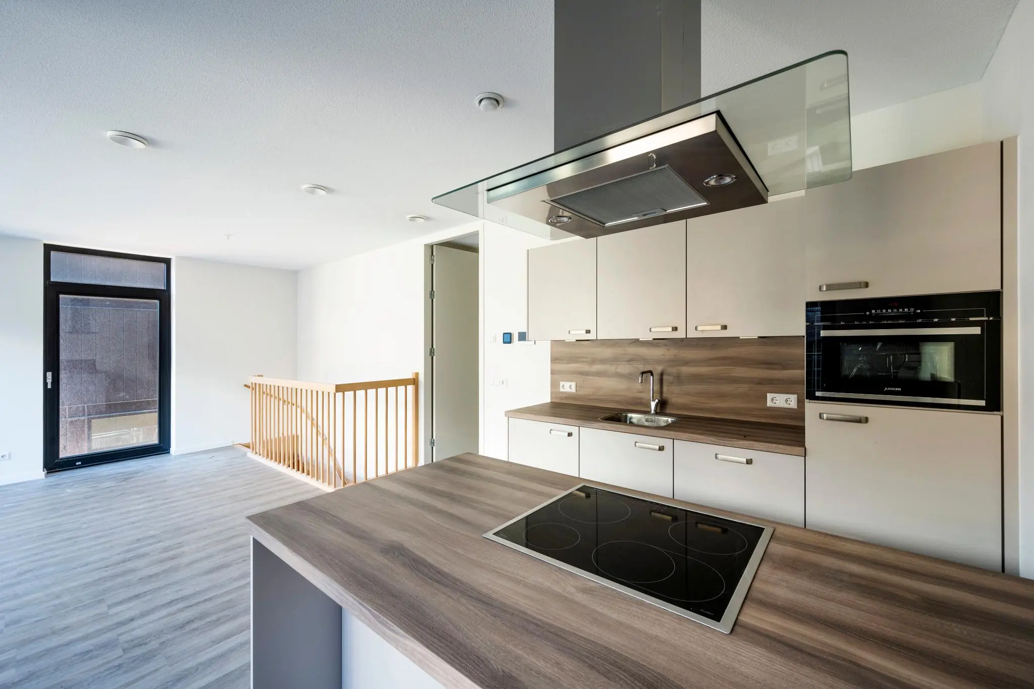 Moderne open keuken aan de Oostenburgermiddenstraat met inductiekookplaat, inbouwoven en houtlook werkblad.