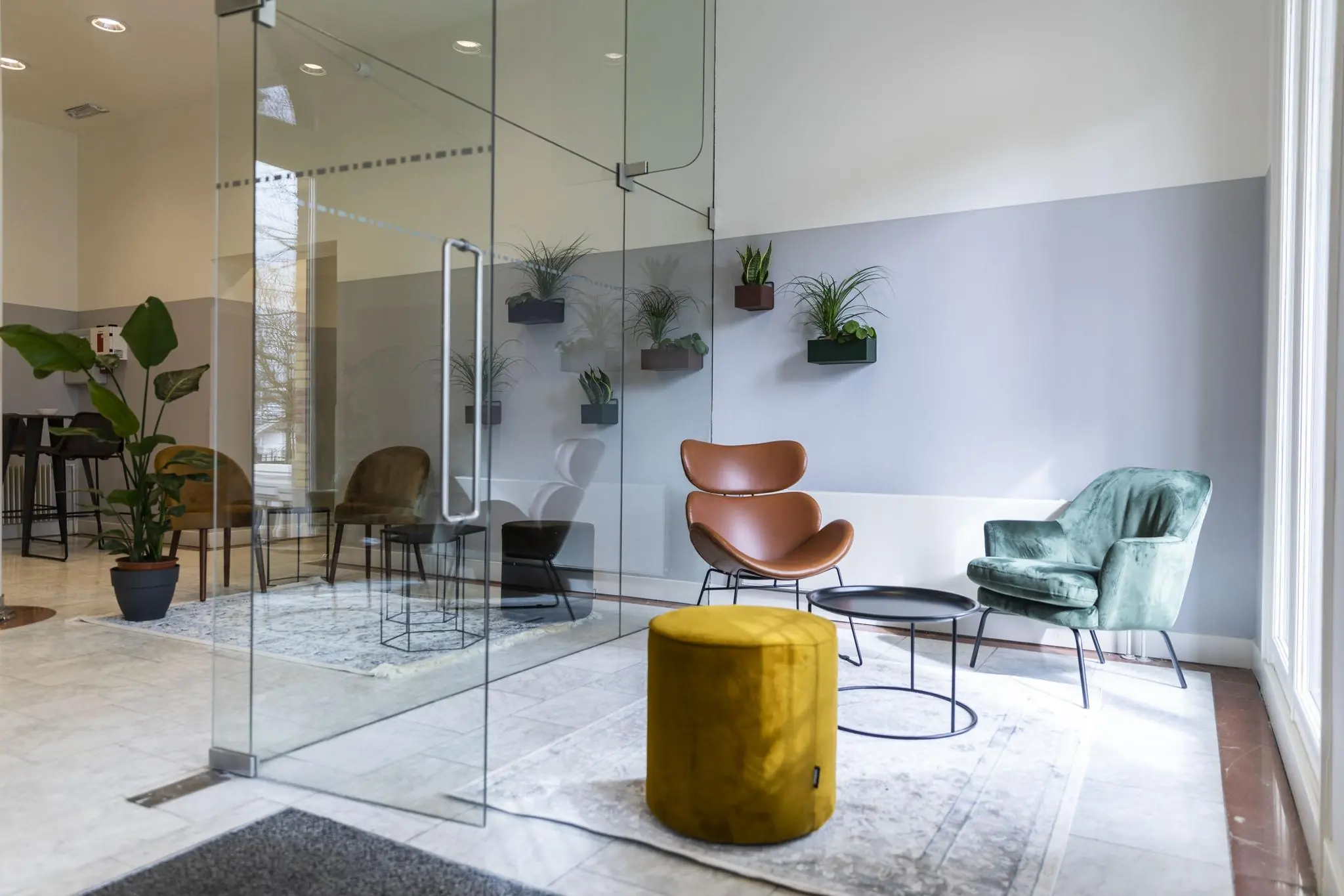 Moderne wachtruimte op Westplein met designstoelen, glazen wand en muurplanten.