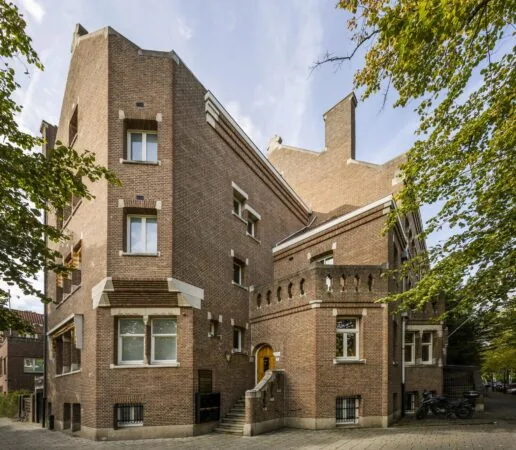 Bakstenen hoekpand aan het Emmaplein met Amsterdamse School-architectuur en een opvallende trapgevel.