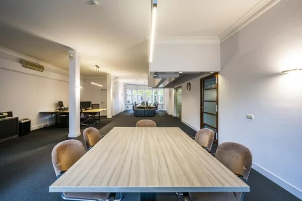 Moderne kantoorruimte aan het Emmaplein met vergadertafel op de voorgrond en werkplekken aan de achterzijde.