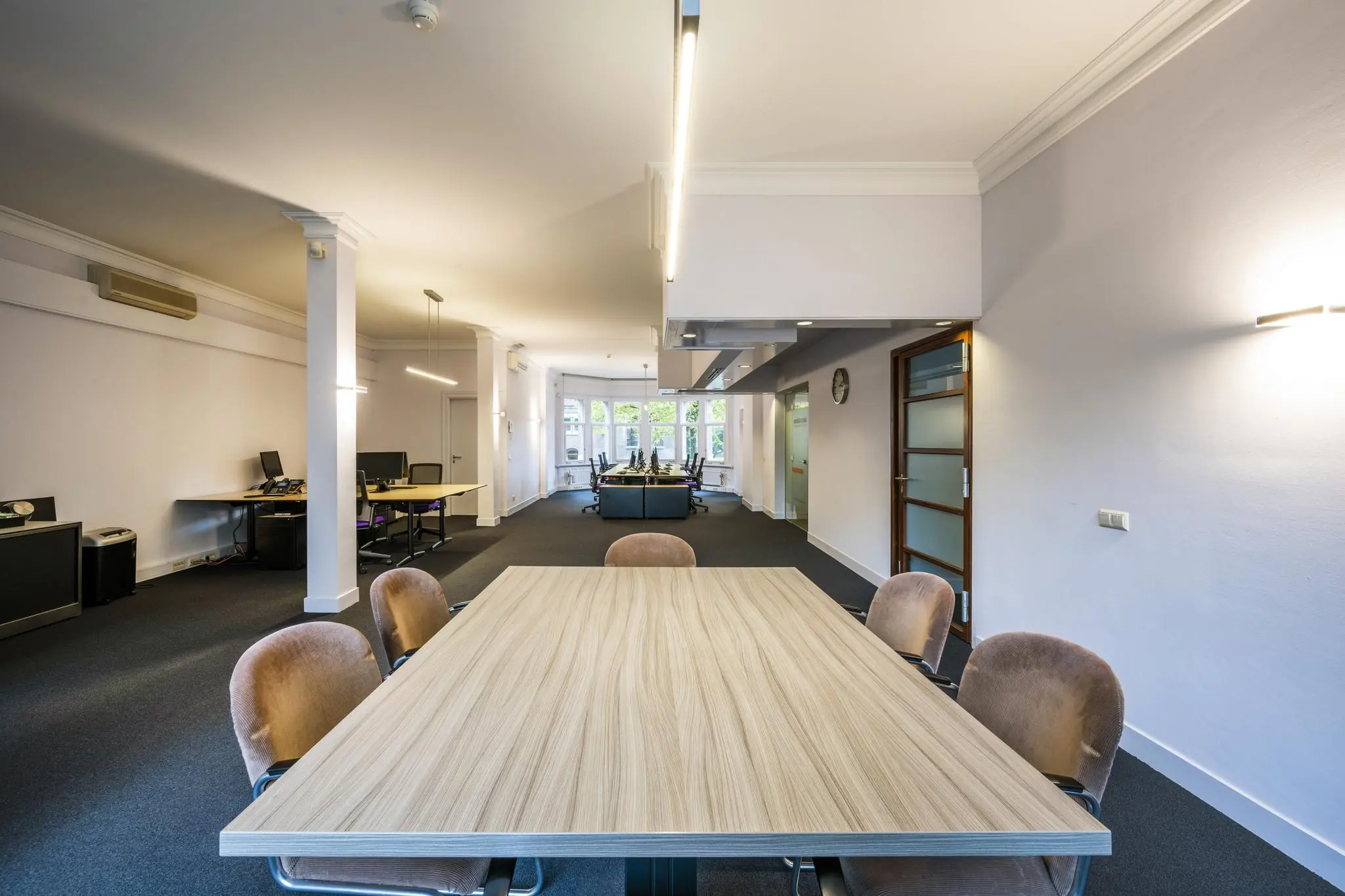 Moderne kantoorruimte aan het Emmaplein met vergadertafel op de voorgrond en werkplekken aan de achterzijde.