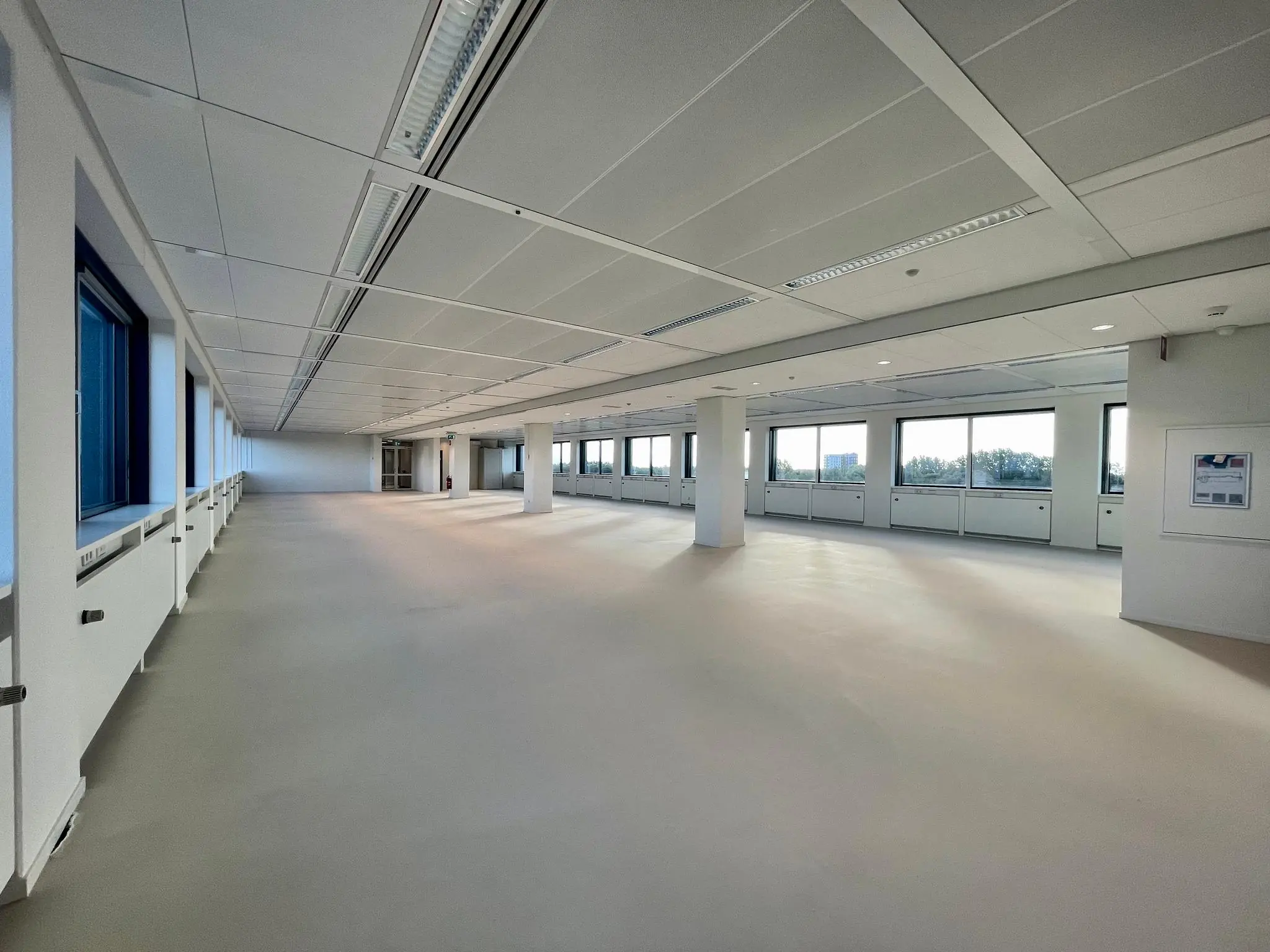 Licht en ruim leeg kantoorpand aan de Nevelgaarde met grote ramen en systeemplafond.