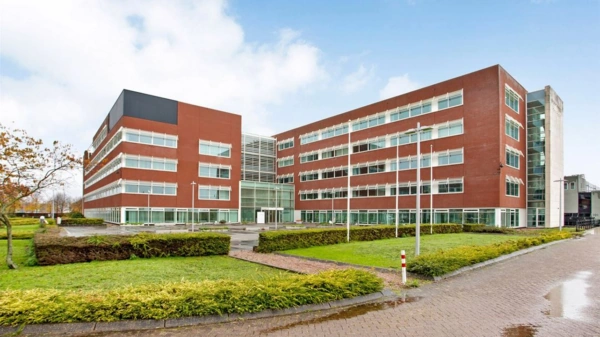 Modern kantoorgebouw aan de Tupolevlaan met rode bakstenen gevel en grote ramen.