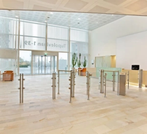 Ingangshal van een modern kantoorgebouw aan de Tupolevlaan met glazen draaideur, toegangspoortjes en een lichte, open inrichting.