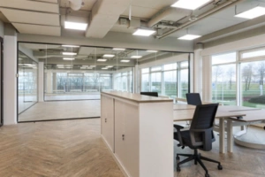 Moderne kantooruimte aan de Tupolevlaan met glazen vergaderruimte en werkplekken bij grote ramen.