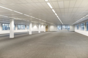 Leeg kantoorpand aan de Tupolevlaan met systeemplafond, grijze tapijtvloer en grote ramen.
