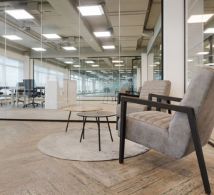 Zitgedeelte met twee grijze stoelen en een ronde salontafel in een modern kantoor aan de Tupolevlaan.
