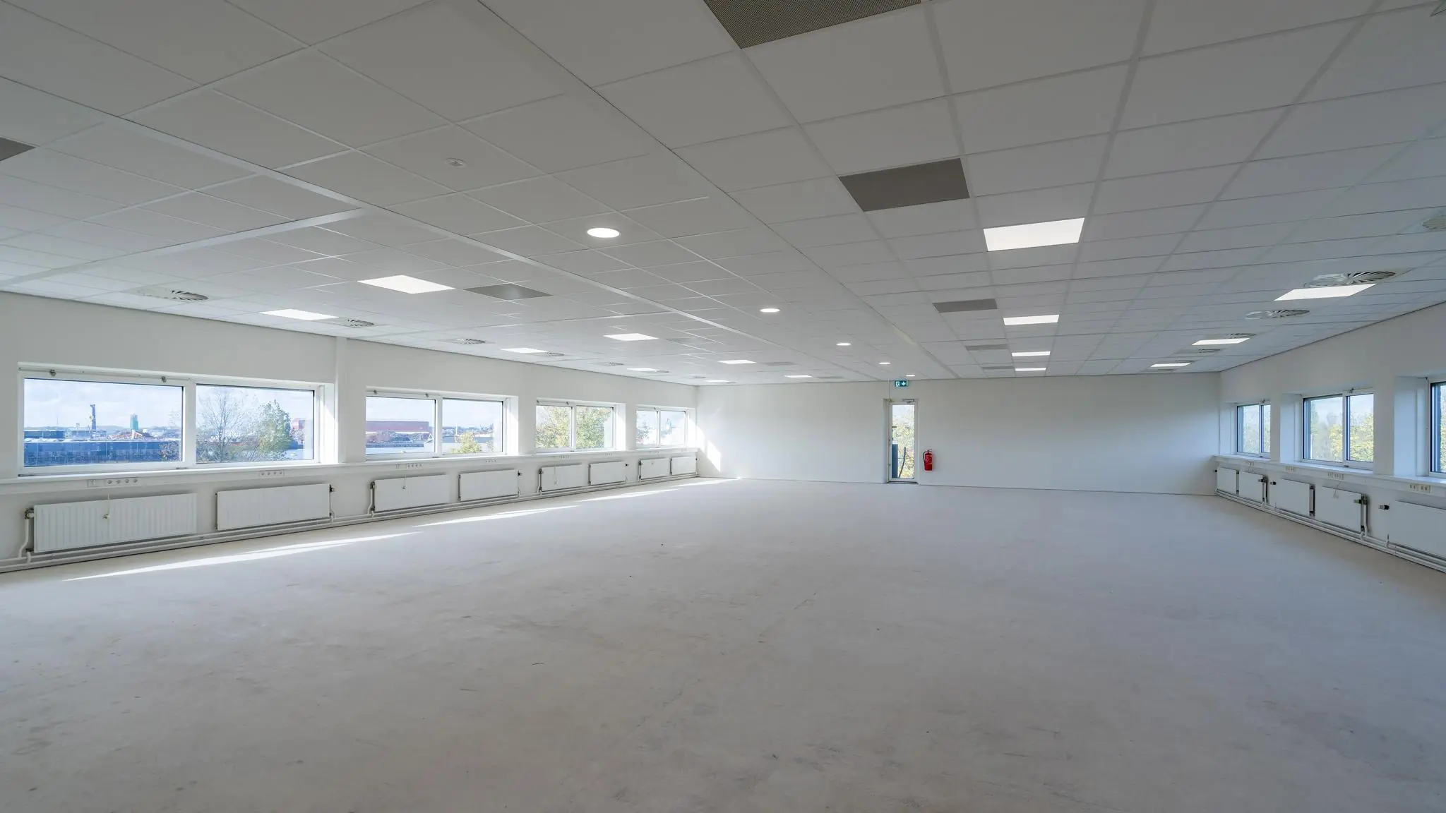 Leeg, licht en ruim kantoorinterieur aan de Mijlweg met grote ramen en systeemplafond.