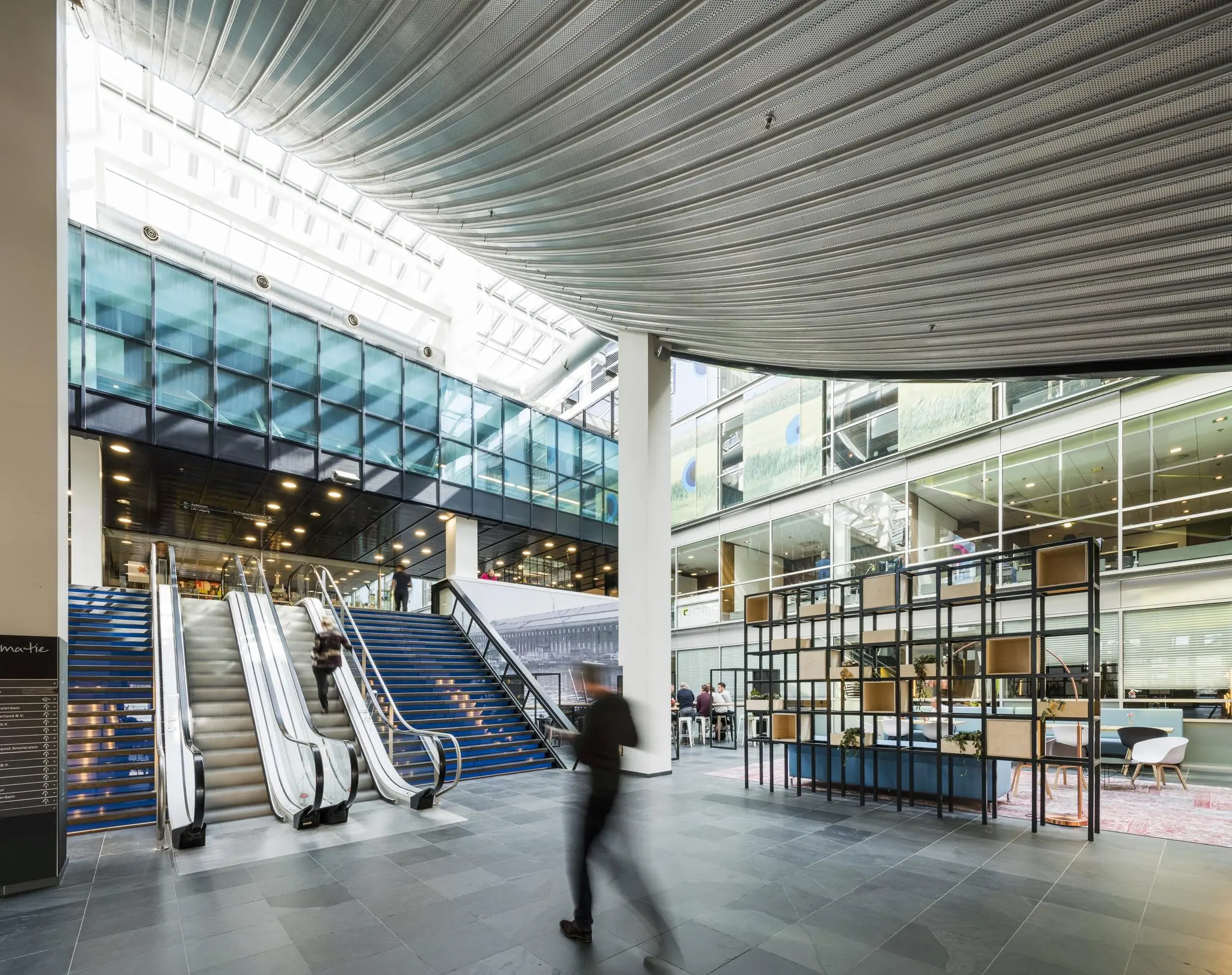 Modern atrium met roltrappen, glazen wanden en kantoren aan de Jacob Bontiusplaats in Amsterdam.