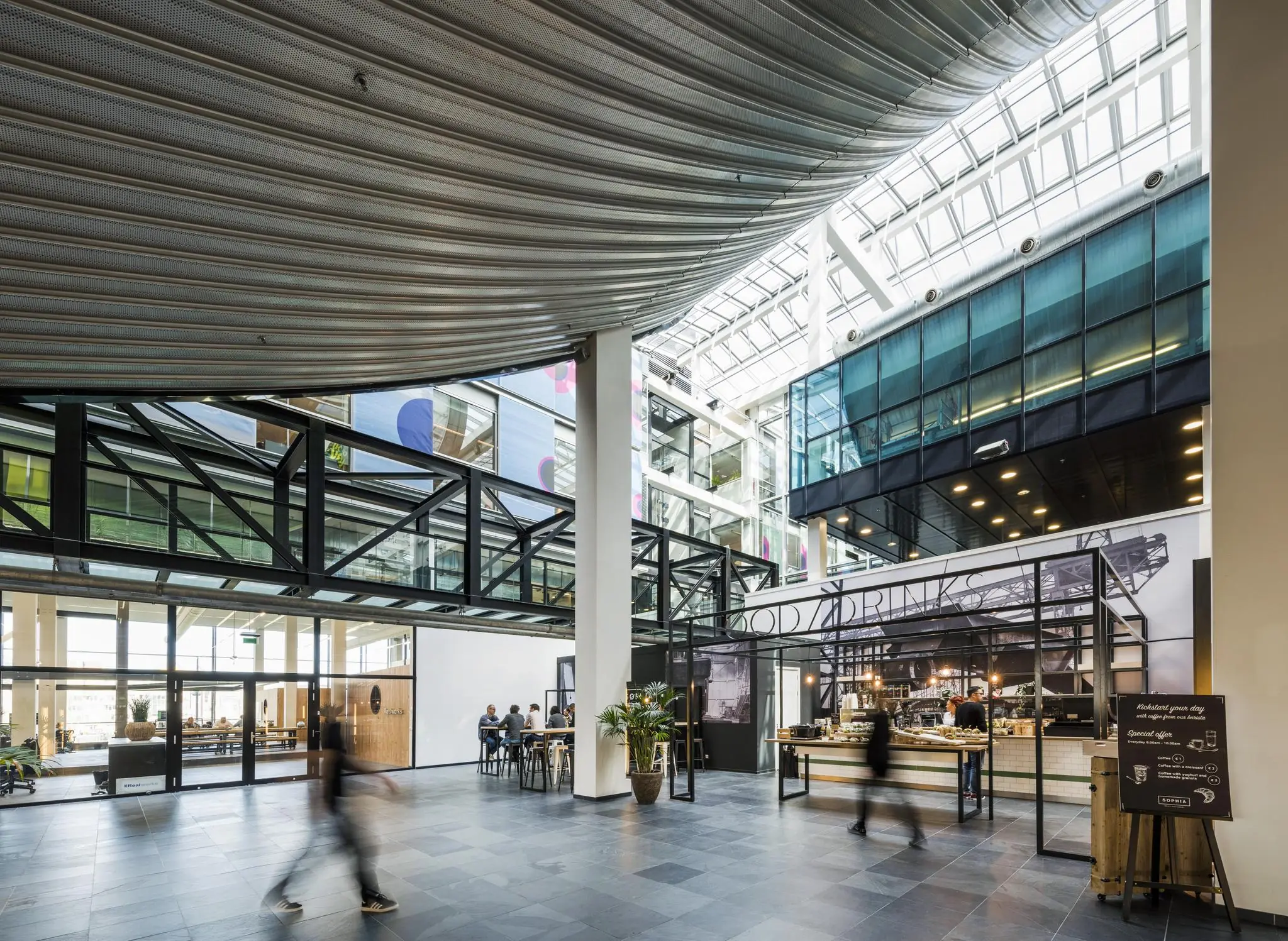 Moderne en lichte binnenruimte aan de Jacob Bontiusplaats met glazen dak, horecagelegenheid en kantoorruimtes.