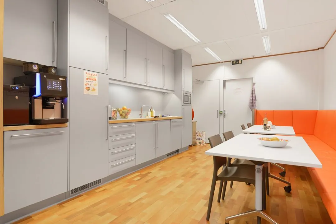Moderne kantine met grijze keuken, koffieautomaat en oranje zithoek aan de Jacob Bontiusplaats.