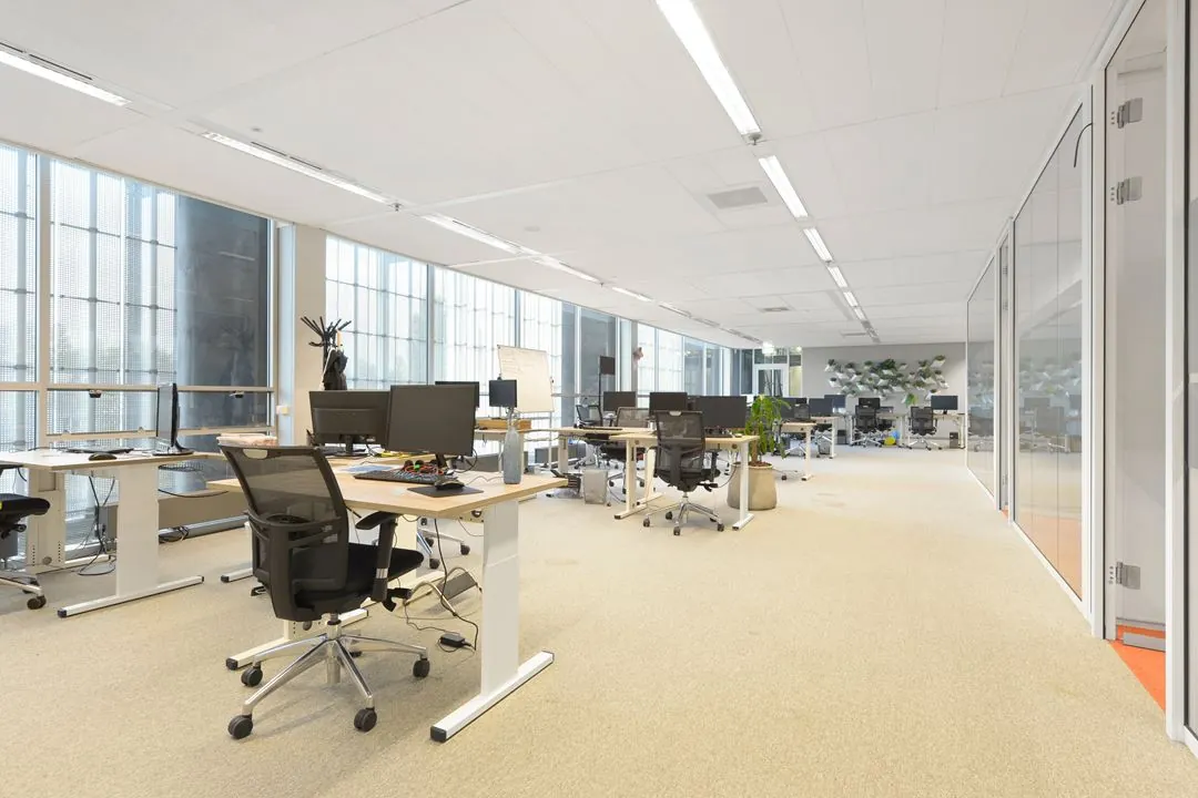 Moderne, lichte kantoorruimte aan de Jacob Bontiusplaats met werkplekken, bureaustoelen en grote ramen.