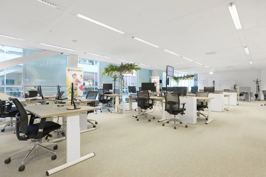Moderne, open kantoorruimte op de Jacob Bontiusplaats met flexwerkplekken, bureaustoelen en hangende planten.