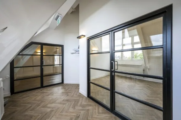 Modern interieur van een kantoorruimte aan de Emmalaan met glazen stalen deuren en visgraat houten vloer.