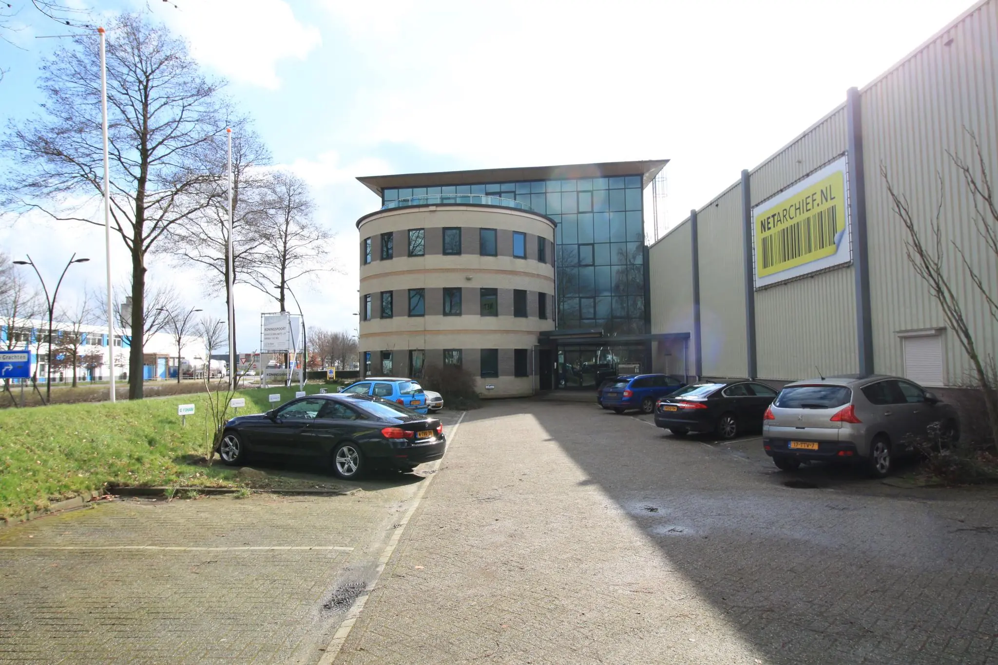 Kantoor- en bedrijfsgebouw aan de Koningsweg met parkeerplaatsen en Netarchive.nl-banner op de gevel.
