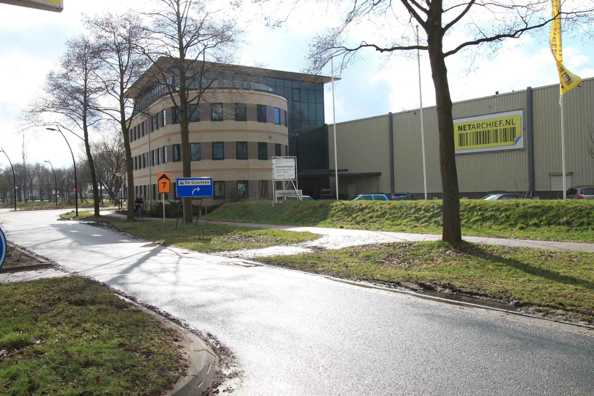 Kantoorgebouw aan de Koningsweg met borden naar bedrijventerrein De Grachten en Netarchief.nl-pand op de achtergrond.