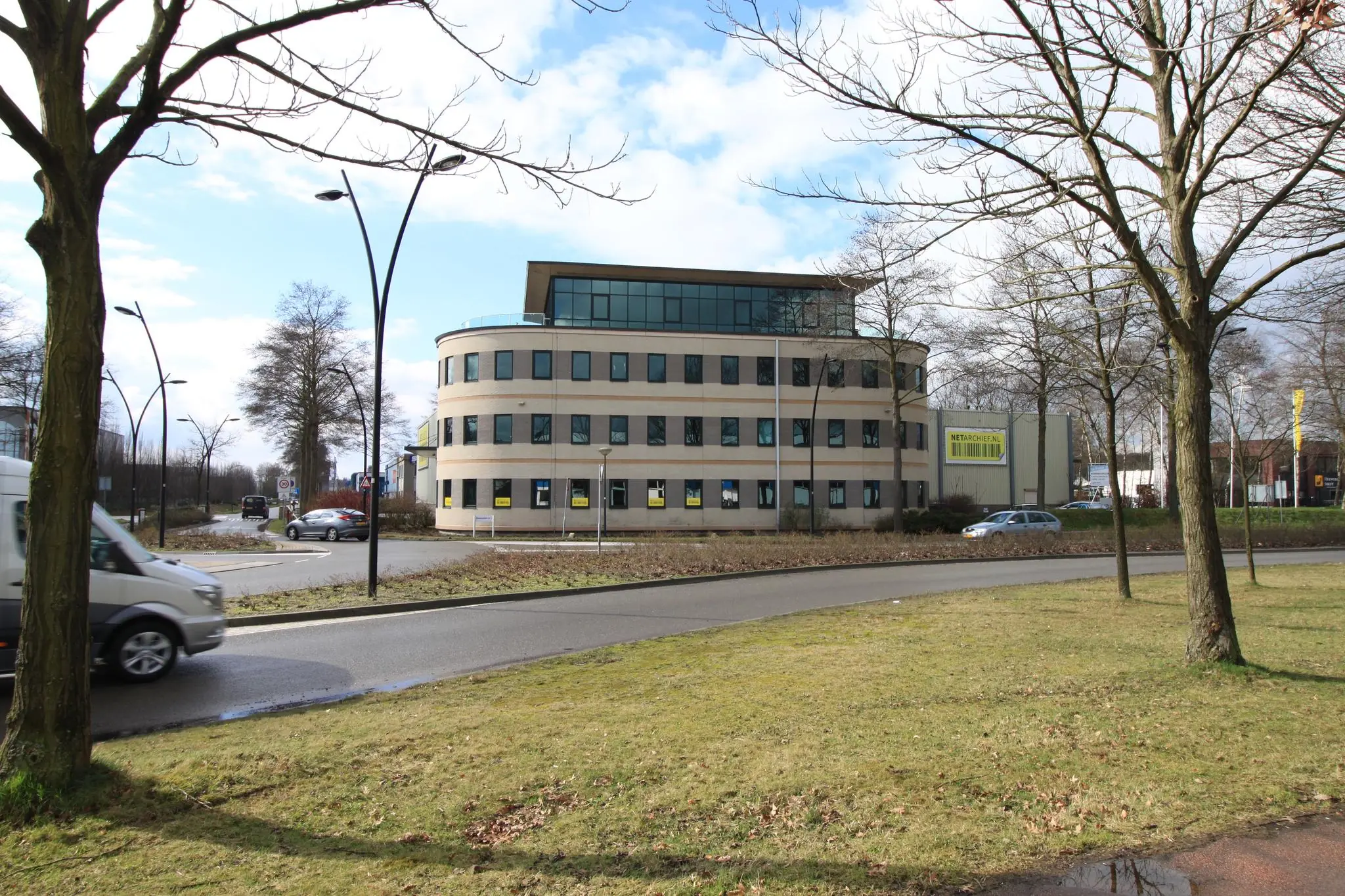 Kantoorpand aan de Koningsweg met ronde gevel en omringd door bomen en een rotonde.