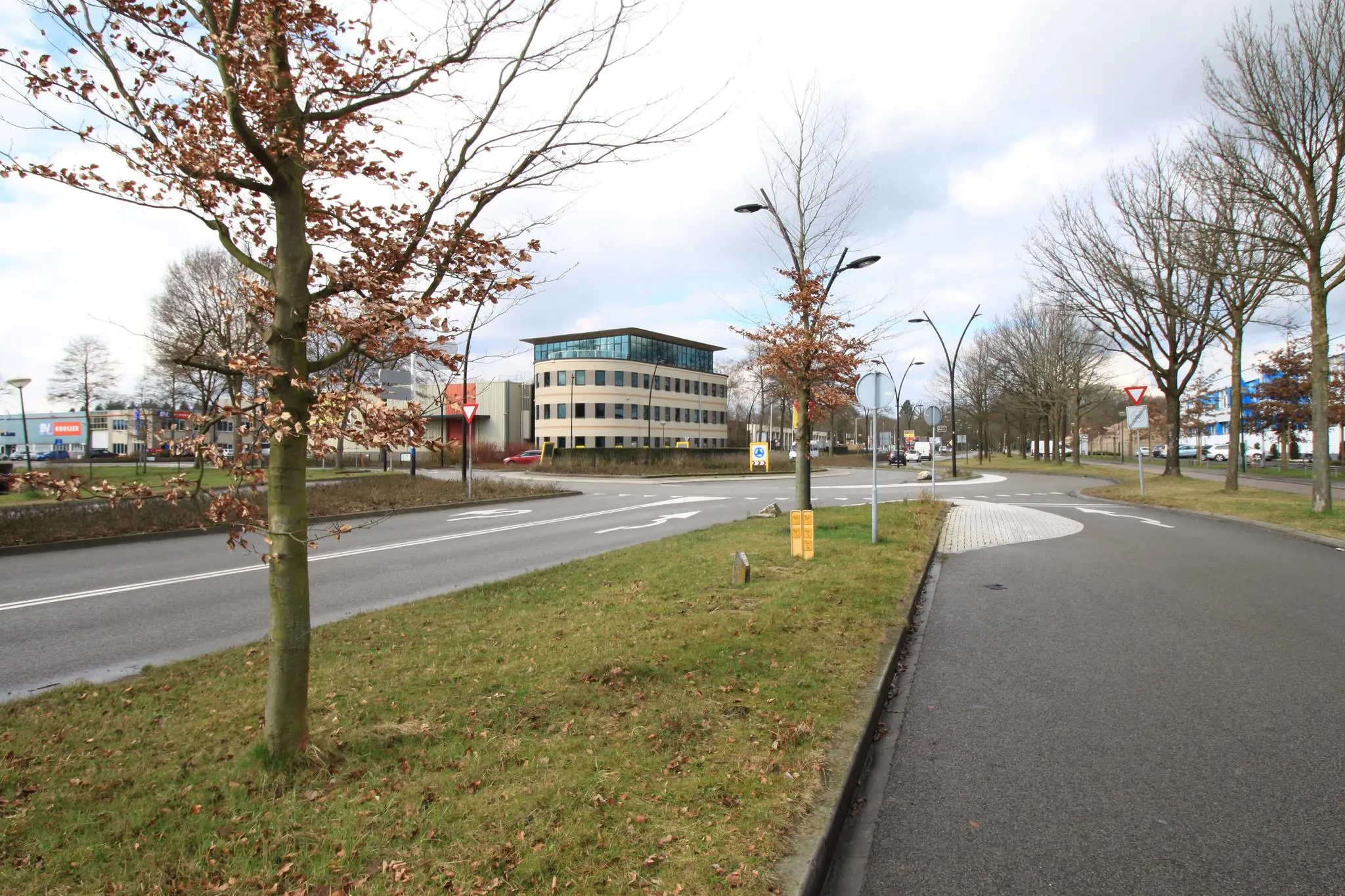 Rotonde op de Koningsweg met omliggende kantoorgebouwen en bomen in wintertoestand.