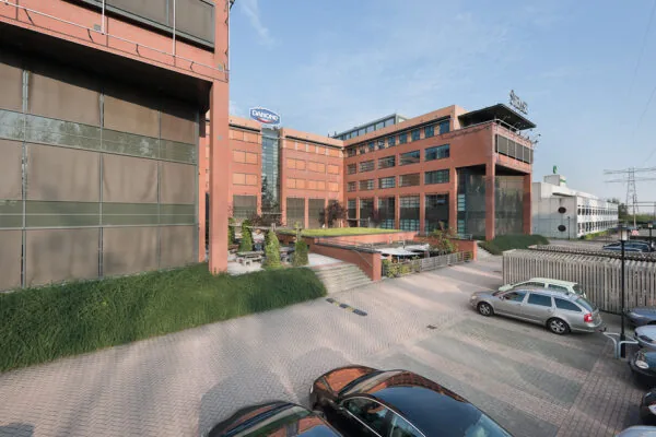Modern kantoorpand aan de Zonnebaan met het Danone-logo op de gevel en een parkeerterrein op de voorgrond.