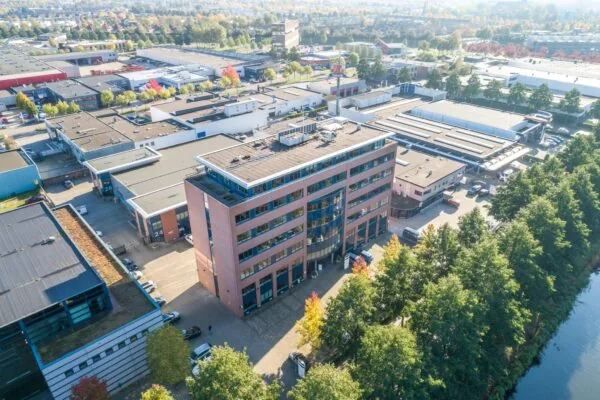 Luchtfoto van een groot rood kantoorgebouw genaamd Astronaut, gelegen op een bedrijventerrein naast een kanaal.